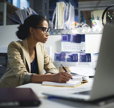 A woman takes notes at her computer.